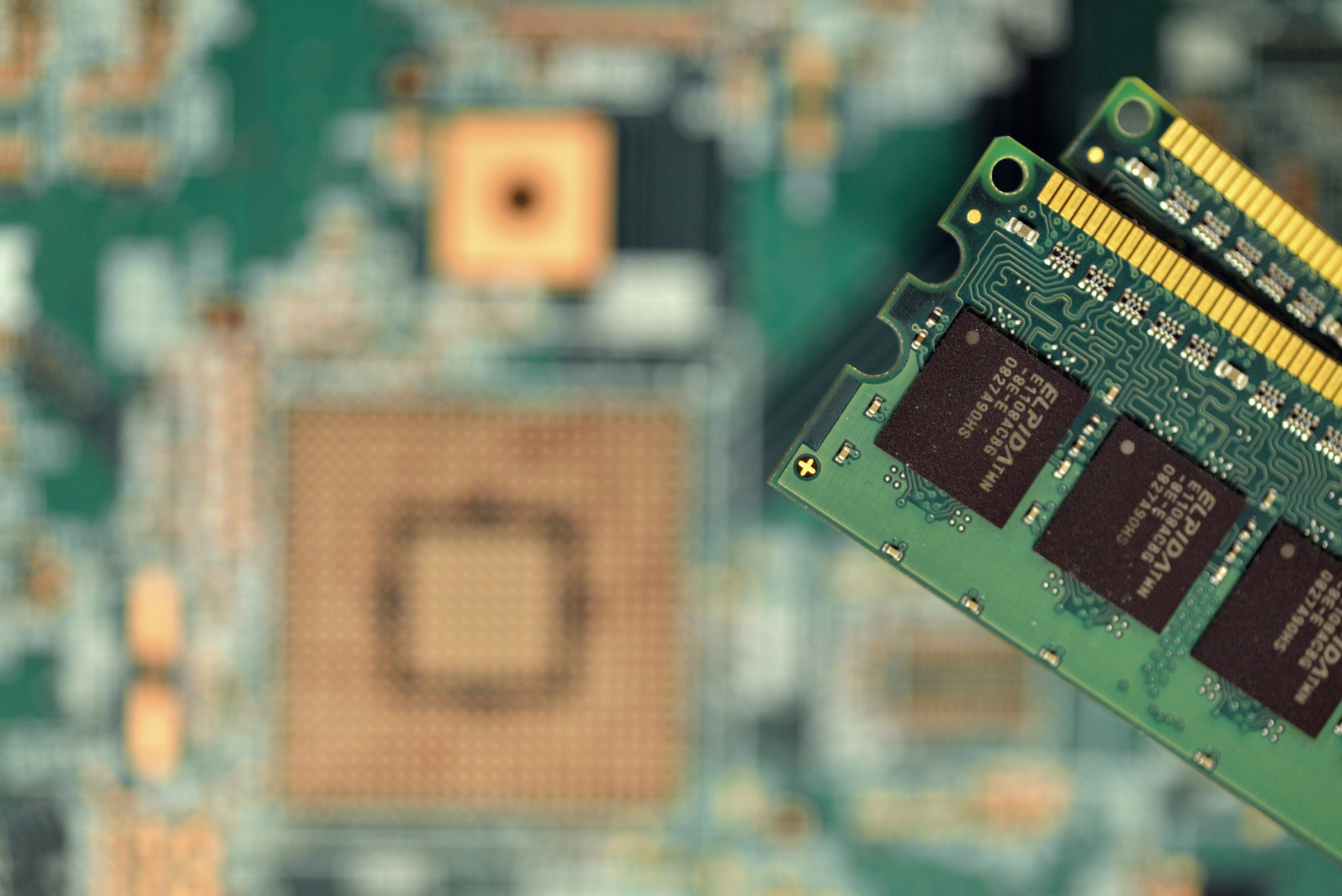 A DRAM module beside a motherboard socket, lit in warm light
